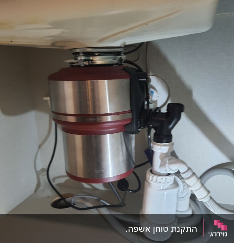 מתקן טוחן אשפה מתחת לכיור עם צינורות חיבור